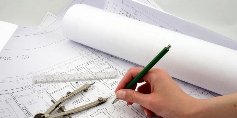 Architect reviewing a floor plan with drafting tools